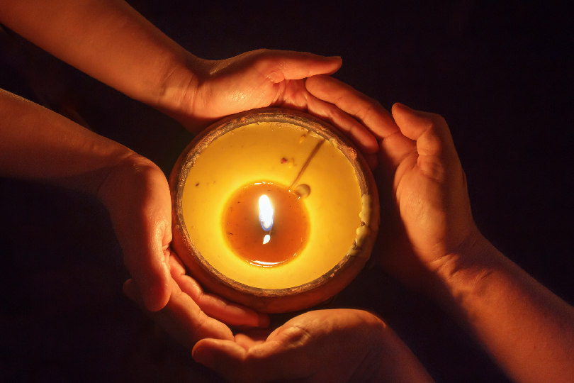 Image of a candle flame flickering between two figures (Spiritual Connections Andheri and Inner Peace)